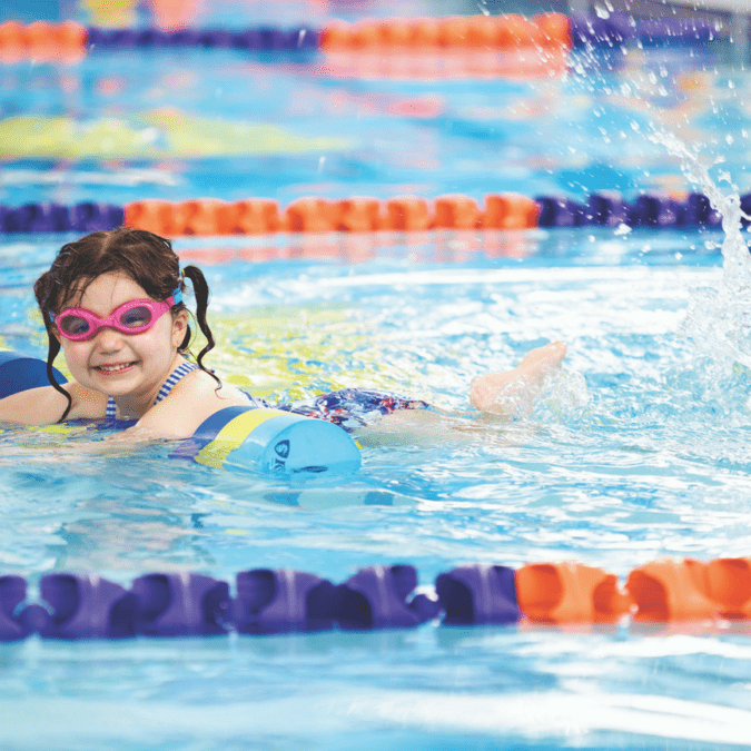 A little girl kicks in the pool at Goldfish Swim School.