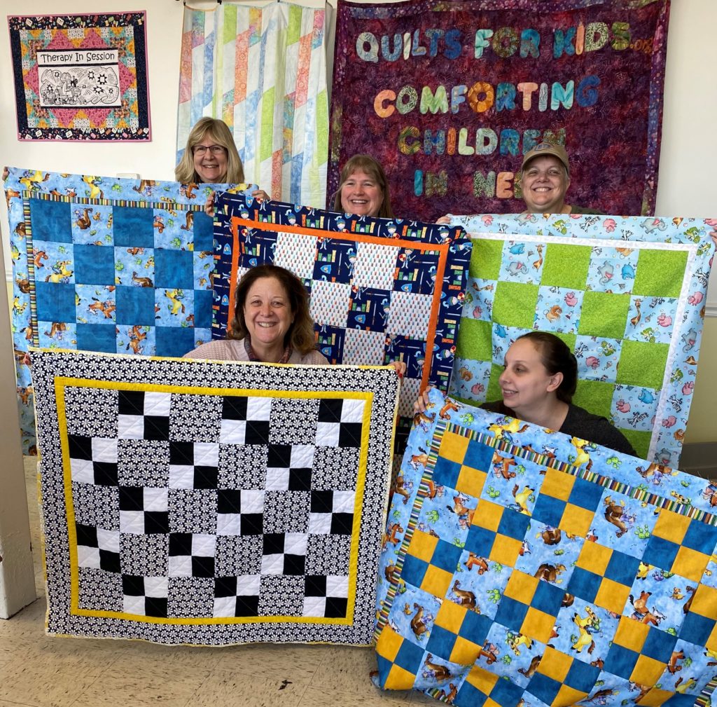 Quilts for kids staff holding up finished quilts