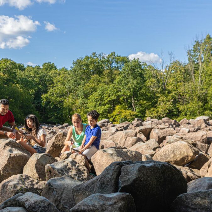 A family of four sit on the rocks with hammers at Ringing Rocks Park in Upper Black Eddy, PA.