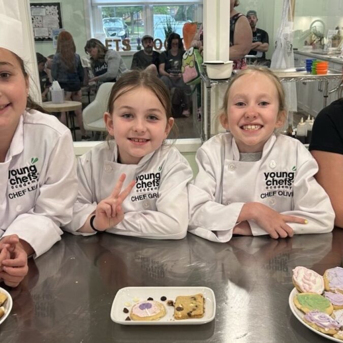 Four girls in chefs gear pose in front of cookies they made at Young Chef's Academy of Yardley.