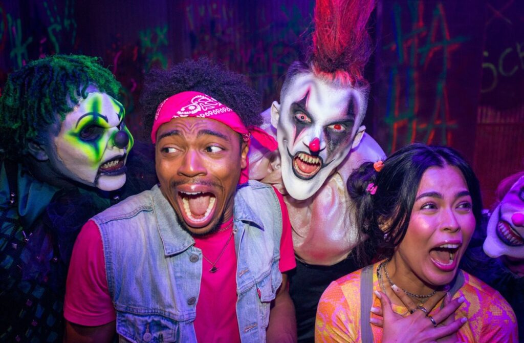 Scary clowns surround two screaming young adults at Six Flags Fright Fest, a Halloween event.