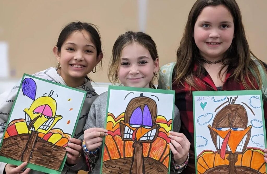 Elementary school girls hold up their turkey drawings at Young Rembrandts Southeastern Pennsylvania.