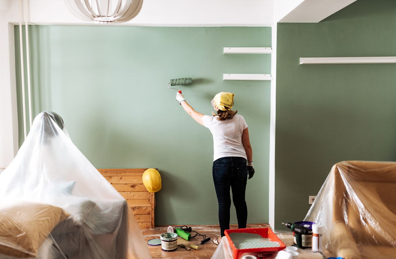 A woman with a head scarf, paints a room green. This is a budget-friendly home upgrade.