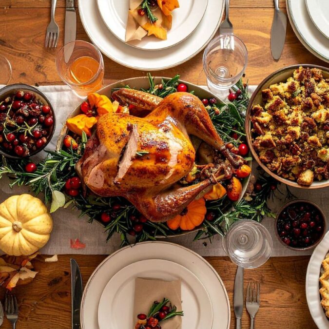 A holiday meal of turkey, sides, and pies are lined up in the center of the table.