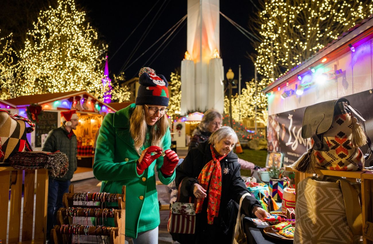 Ladies shop outdoor vendors amid holiday lights at the Easton Winter Village.