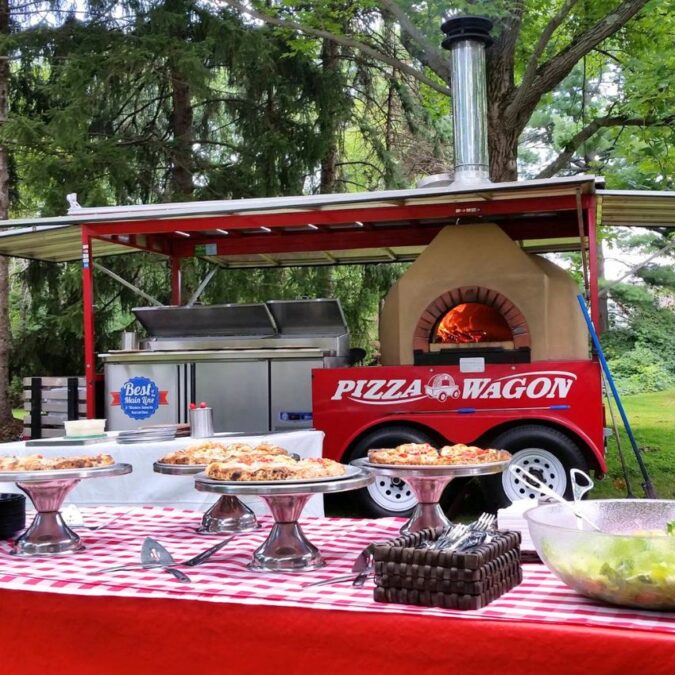 The Pizza Wagon Catering Company is set up in a park ready for party guests to eat.
