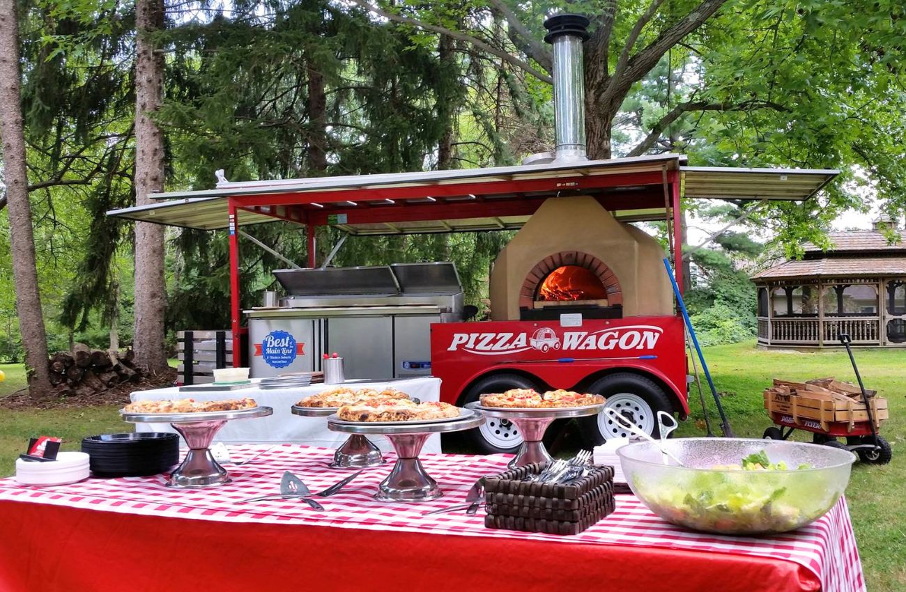 The Pizza Wagon Catering Company is set up in a park ready for party guests to eat.