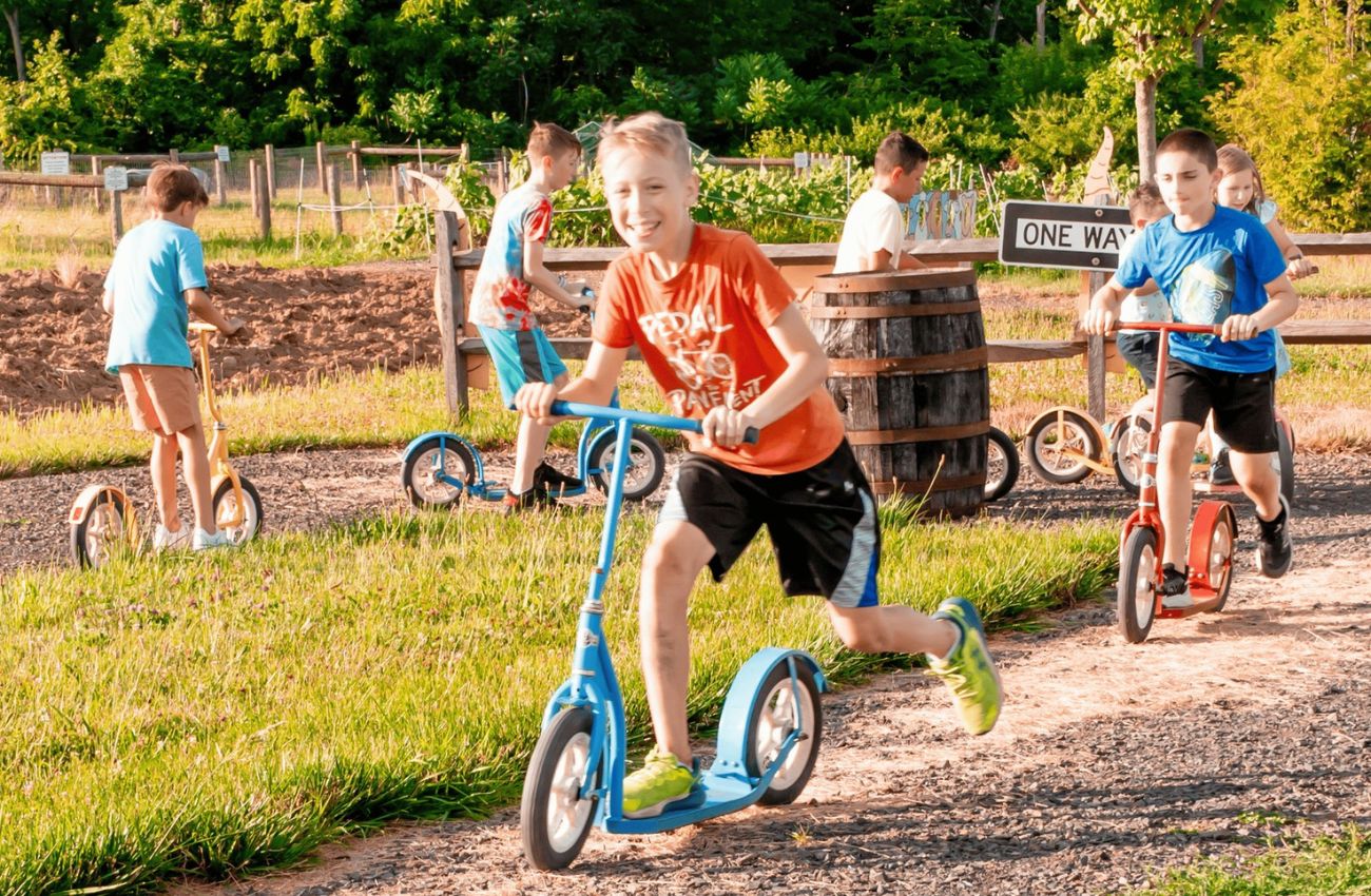 Kids ride scooters on a track at Hellerick's Adventure Farm in Bucks County, PA.