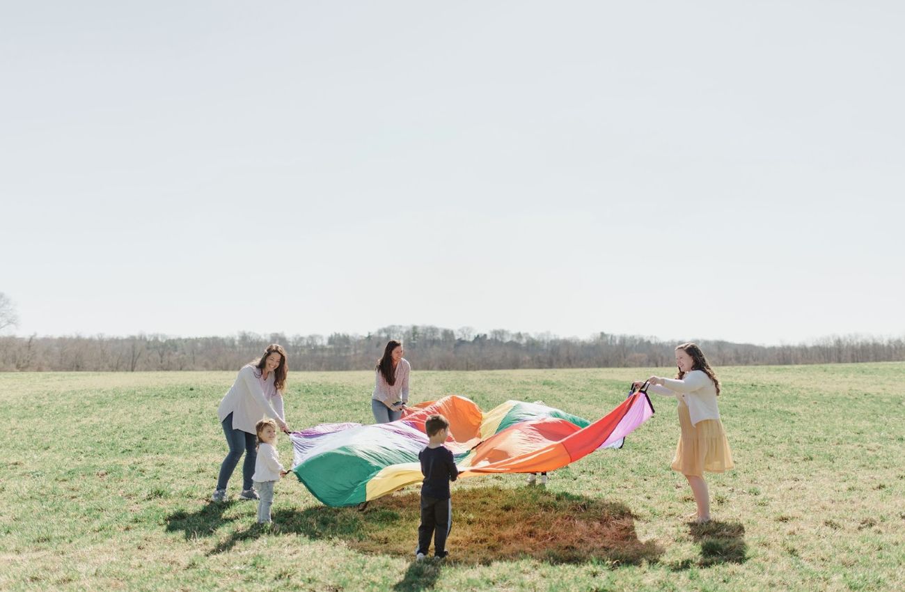 Adults and children hold a rainbow parachute during a Little Music Corner class in Bucks County.