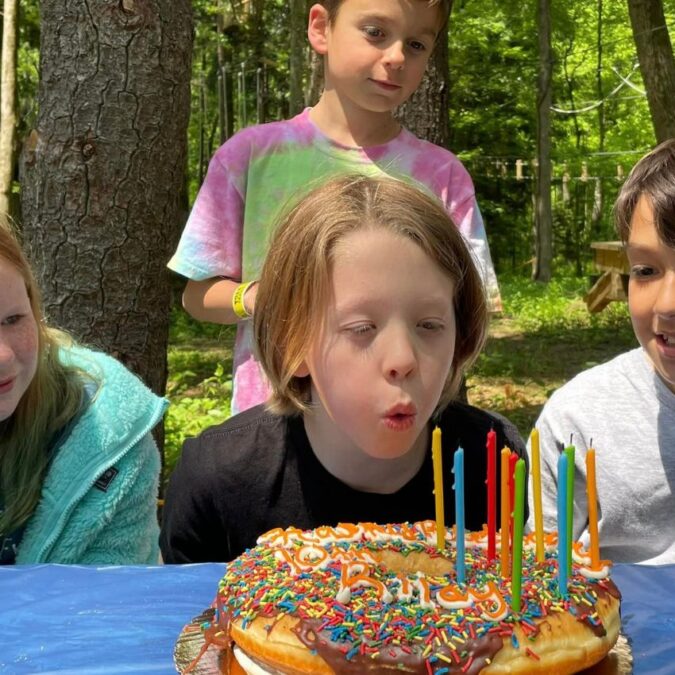 A boy blows out the candles on a birthday cake with friends at TreeTrails Adventures in Trevose, PA