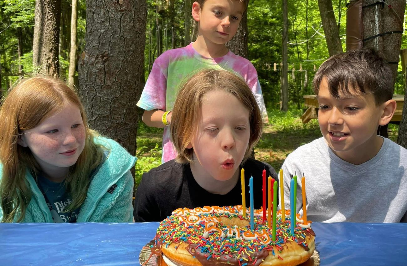 A boy blows out the candles on a birthday cake with friends at TreeTrails Adventures in Trevose, PA