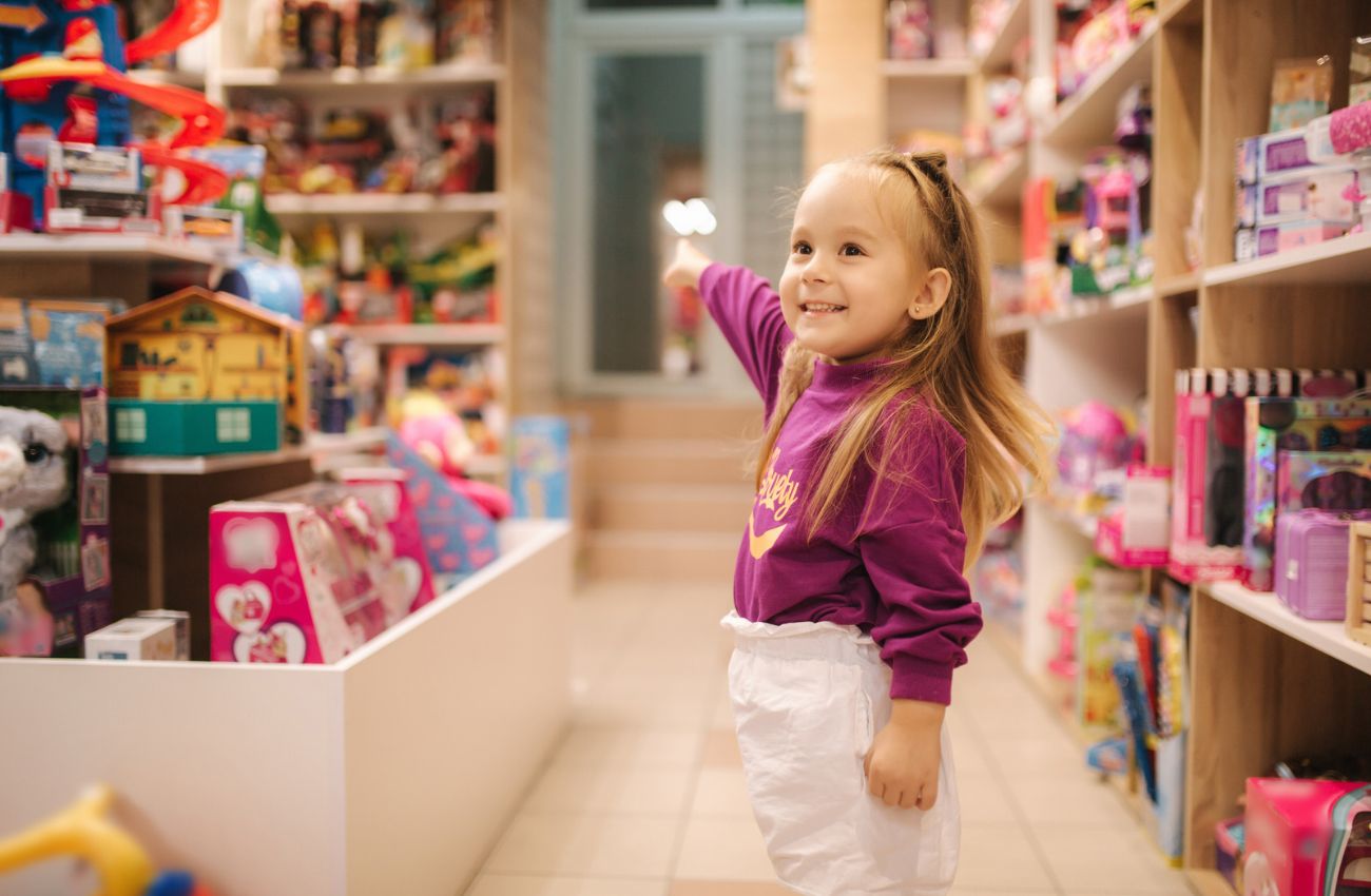 A little girl points at all the toys in a local toy store.